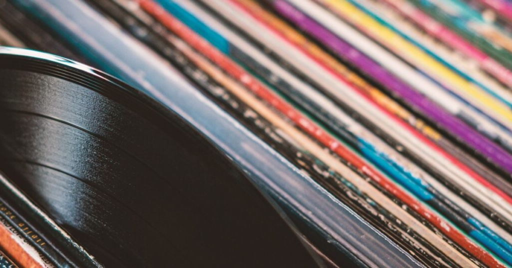 A vinyl record being pulled out of a stack of record sleeves